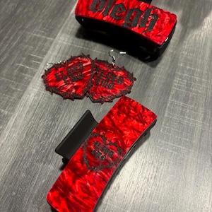 May include: Three red and black hair clips with gothic-style text. The clips feature a heart with barbed wire and the text "Elder Emo" and "Bleh".