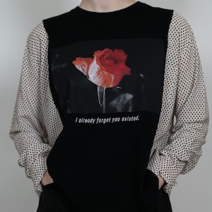 Könnte beinhalten: Schwarzes Langarmshirt mit einem großen Aufdruck einer roten Rose auf der Vorderseite. Das Shirt hat gemusterte Ärmel und den Text "I already forgot you existed" unter der Rose.