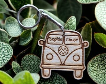 May include: A wooden keychain shaped like a vintage Volkswagen bus with the names "Sophie" and "Oliver" engraved on the windows. The keychain is attached to a silver metal ring.