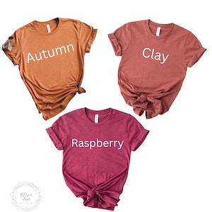 Puede incluir: Tres camisetas de diferentes colores con las palabras "Oto&ntilde;o", "Arcilla" y "Frambuesa" impresas en ellas.