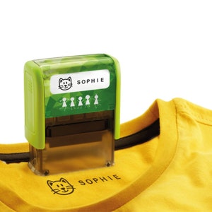 May include: Green and clear self-inking stamp with a cat and the name "Sophie" on a white label. The stamp is being used to stamp a yellow t-shirt with the same design.