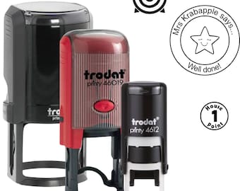 May include: A collection of self-inking stamps in black and red, with the brand name "Trodat" visible. Additional stamps include a target, a star with the text "Well done!", and a stamp with "House 1 Point".
