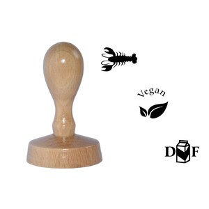 May include: Wooden stamp with a lobster, vegan, and dairy-free symbols. The stamp is brown and has a round base.