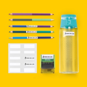 May include: A set of colorful pencils, a clear water bottle with a blue lid, a sheet of white labels, and a green self-inking stamp with the text "ANNA VAN LEUR" on it. The labels and stamp are for personalizing items.