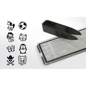 May include: A black plastic stamp with a variety of alphabet letters, numbers, and symbols. The stamp also includes a set of small, black and white images, including a unicorn, a soccer ball, a mermaid, a cat, a butterfly, a penguin, a pirate skull and crossbones, and an elephant. A black plastic tool with a handle and two prongs is used to select the desired stamp.