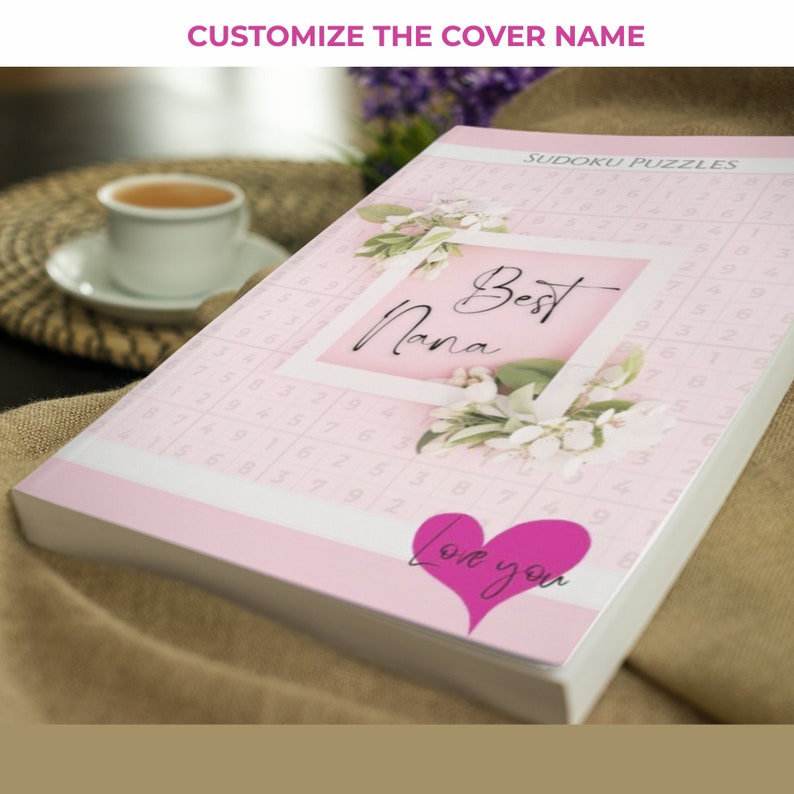 May include: A pink book with a floral design and the text "Best Nana" in a white frame. The book also has the text "Love you" in a pink heart shape. The book is titled "Sudoku Puzzles".