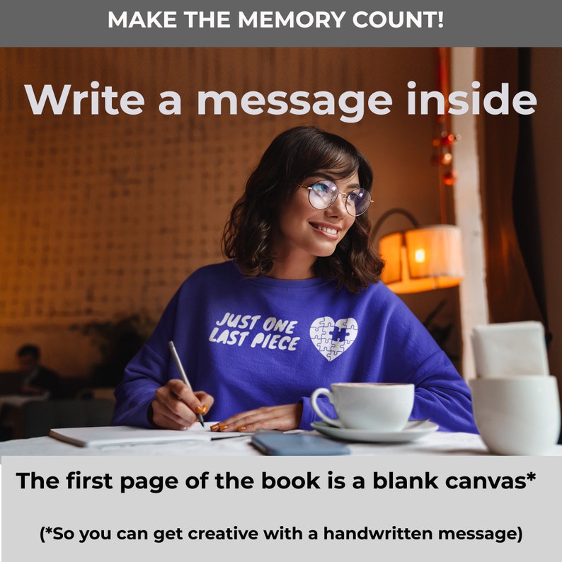 May include: A woman wearing a purple sweatshirt with the text "Just One Last Piece" and a puzzle piece heart design is writing in a notebook. She is sitting at a table with a cup of coffee and a phone.