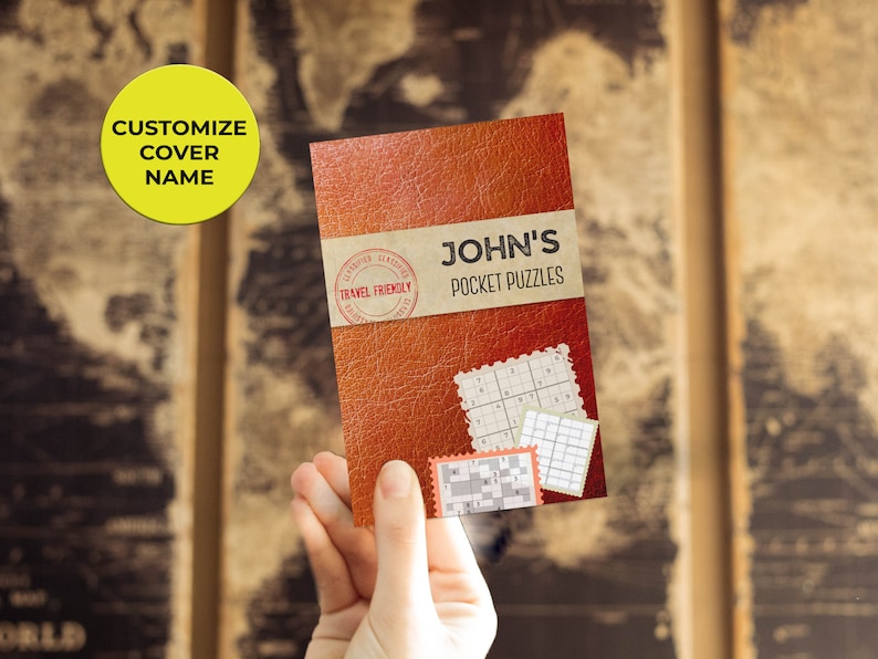Może przedstawiać: Brązowa książka w sk&oacute;rzanej oprawie z tytułem "JOHN'S POCKET PUZZLES" i czerwoną pieczątką "TRAVEL FRIENDLY". Na okładce książki widać kilka siatek łamigł&oacute;wek.