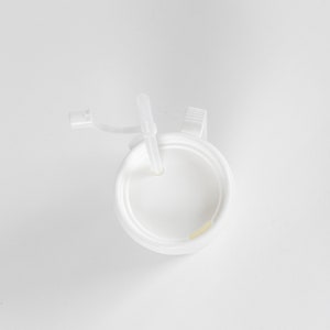 May include: White plastic cup with a lid and a straw. The lid has a small handle.
