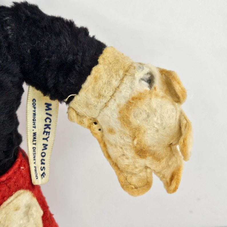 May include: Vintage Mickey Mouse plush toy with a black fur body, red shorts, and white gloves. The toy has a tag that reads "MICKEY MOUSE COPYRIGHT WALT DISNEY PROD."
