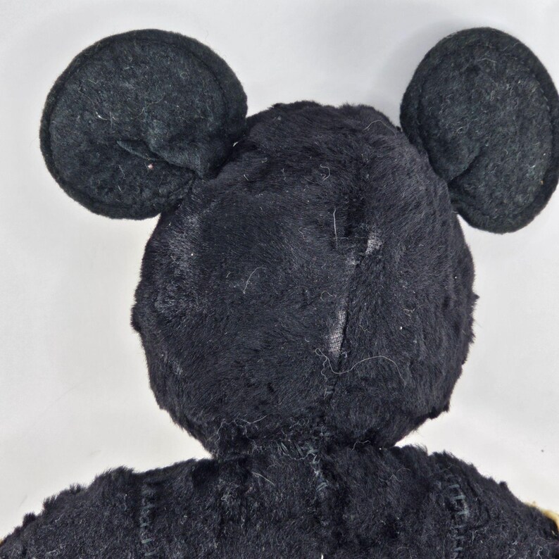 May include: Black plush toy with large ears shaped like Mickey Mouse's ears.