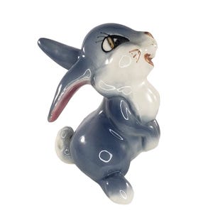 May include: A blue and white ceramic figurine of a rabbit with a pink nose and large eyes. The rabbit is standing on its hind legs and has its front paws raised.