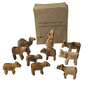 May include: A set of hand-carved olive wood figurines, including a camel, donkey, sheep, and a figure, with a cardboard box. The box reads "HAND CARVED OF OLIVE WOOD BETHLEHEM - THE HOLY LAND" and "No. c60".