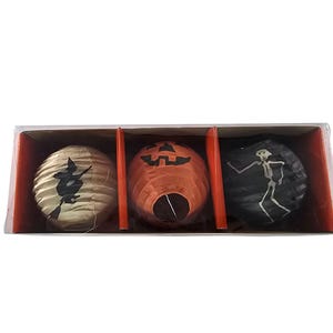 May include: A boxed set of three Halloween paper lanterns. The lanterns are decorated with a witch, a pumpkin face, and a skeleton. The colours are orange, black, and cream.