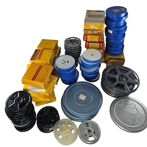 Puede incluir: Una colección de carretes de película y cajas de película vintage. Los carretes son de varios colores, incluyendo negro, gris y azul. Las cajas de película son amarillas y marrones. La imagen muestra una variedad de artículos relacionados con el cine.