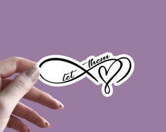 May include: A white sticker with a black infinity symbol and the words "let them" inside the symbol. A heart is attached to the infinity symbol. The sticker is being held by a hand against a purple background.