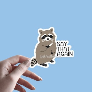 May include: A 3.0" x 2.75" sticker featuring a cartoon raccoon holding a knife with the text "Say that again".