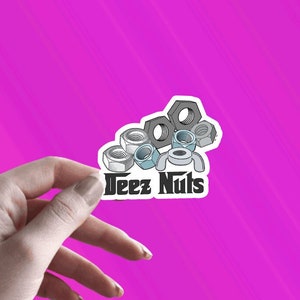 May include: A white sticker with a cartoon image of a pile of nuts and bolts. The text "Deez Nuts" is below the image. The text "WashYourMouthGifts" is below the sticker.