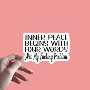 May include: A white sticker with black text that reads "Inner peace begins with four words: Not my fucking problem." The sticker is 3 inches by 2 inches.