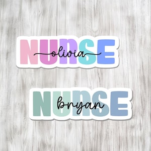 May include: Two stickers with the word "NURSE" in pastel colors. The top sticker has the name "olivia" in cursive, and the bottom sticker has the name "bryan" in cursive. The stickers are on a light wood background.