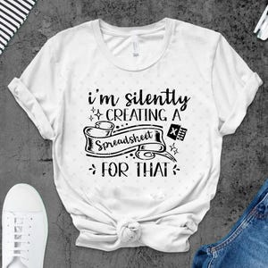 Puede incluir: Camiseta blanca con el texto negro "I'm silently creating a spreadsheet for that". El diseño incluye una taza de café, una pancarta con la palabra "Spreadsheet", un icono "X" y un icono de calculadora. La camiseta se combina con vaqueros azules y zapatillas blancas.