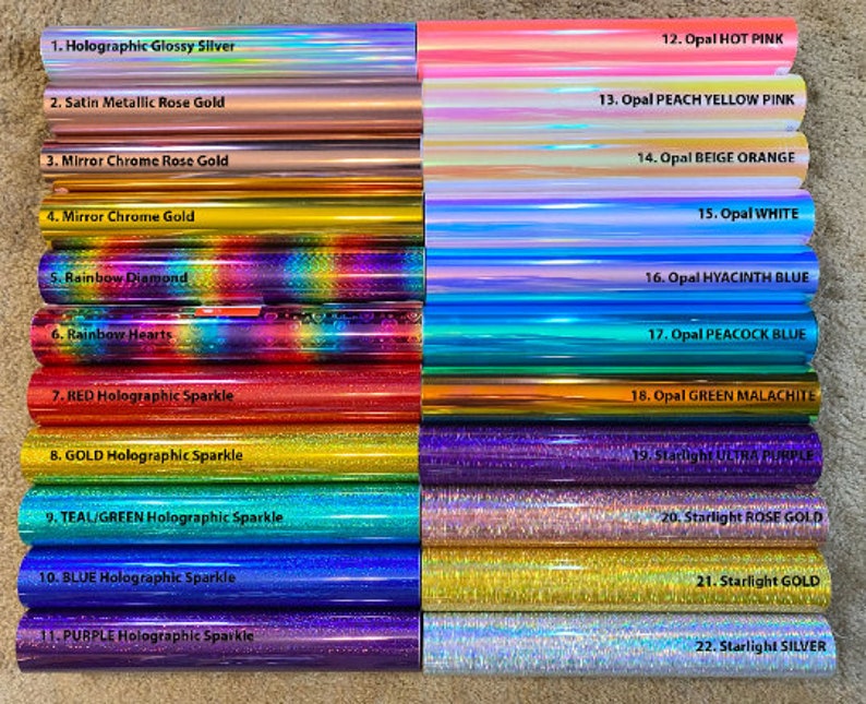 May include: A close-up of 22 different rolls of holographic vinyl, each with a different color and pattern. The vinyl is labeled with numbers and names, such as "Holographic Glossy Silver", "Satin Metallic Rose Gold", "Opal HOT PINK", and "Starlight SILVER".