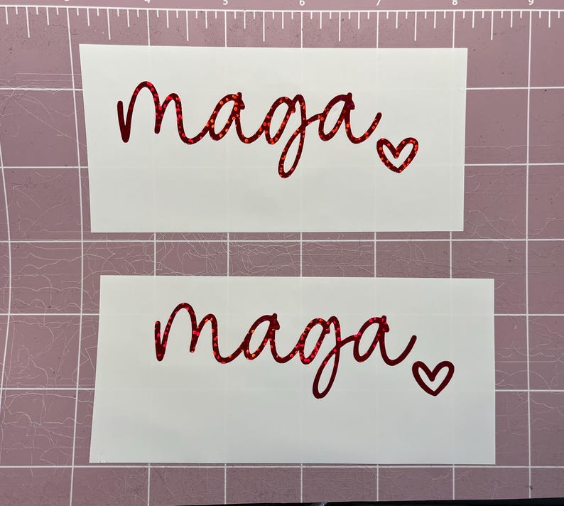 May include: Two white sheets of paper with the word "maaja" written in red glitter lettering with a small red glitter heart next to it.