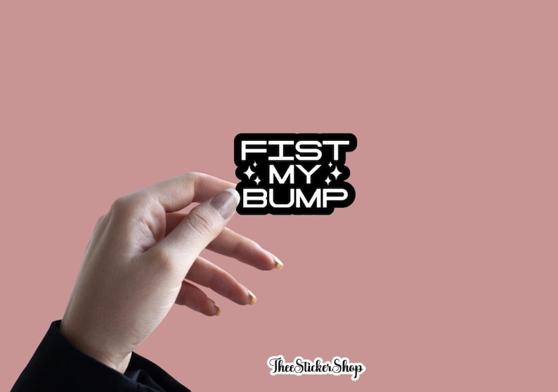 May include: A black and white sticker with the text "FIST MY BUMP" in a bold, blocky font. The sticker has a white border and star accents. The background is a solid, muted pink.