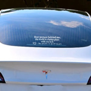 May include: White Tesla Model 3 with a rear window sticker that reads "Dear person behind me, the world is a better place with you in it - The people who drive in front of you"
