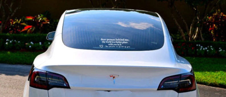 May include: White Tesla Model 3 with a rear window sticker that reads "Dear person behind me, the world is a better place with you in it - The people who drive in front of you"