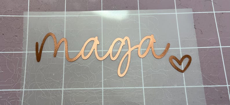 May include: A copper-coloured vinyl decal with the word "naaja" written in a cursive font and a small heart to the right of the word.
