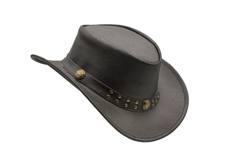 K&ouml;nnte beinhalten: Ein schwarzer Cowboyhut aus Leder mit einem dekorativen Band mit Metallnieten und einem kleinen Metalldesign. Der Hut hat eine breite Krempe und eine hohe Krone.