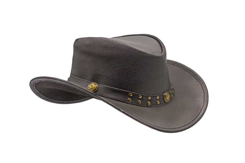 K&ouml;nnte beinhalten: Ein schwarzer Cowboyhut aus Leder mit einem braunen Lederband und dekorativen Metallapplikationen.