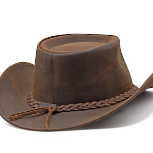 May include: A brown leather cowboy hat with a braided leather band and a leather strap.