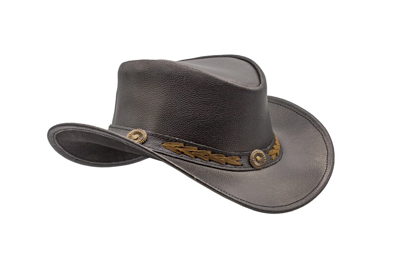 K&ouml;nnte beinhalten: Ein schwarzer Cowboyhut aus Leder mit einem braunen Lederband und Metallverzierungen.