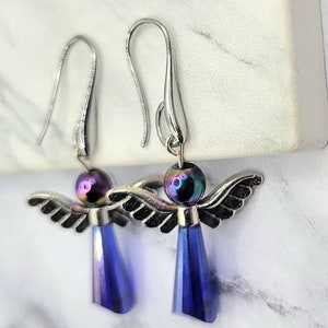 May include: A pair of silver angel dangle earrings with iridescent purple beads and blue crystal drops.