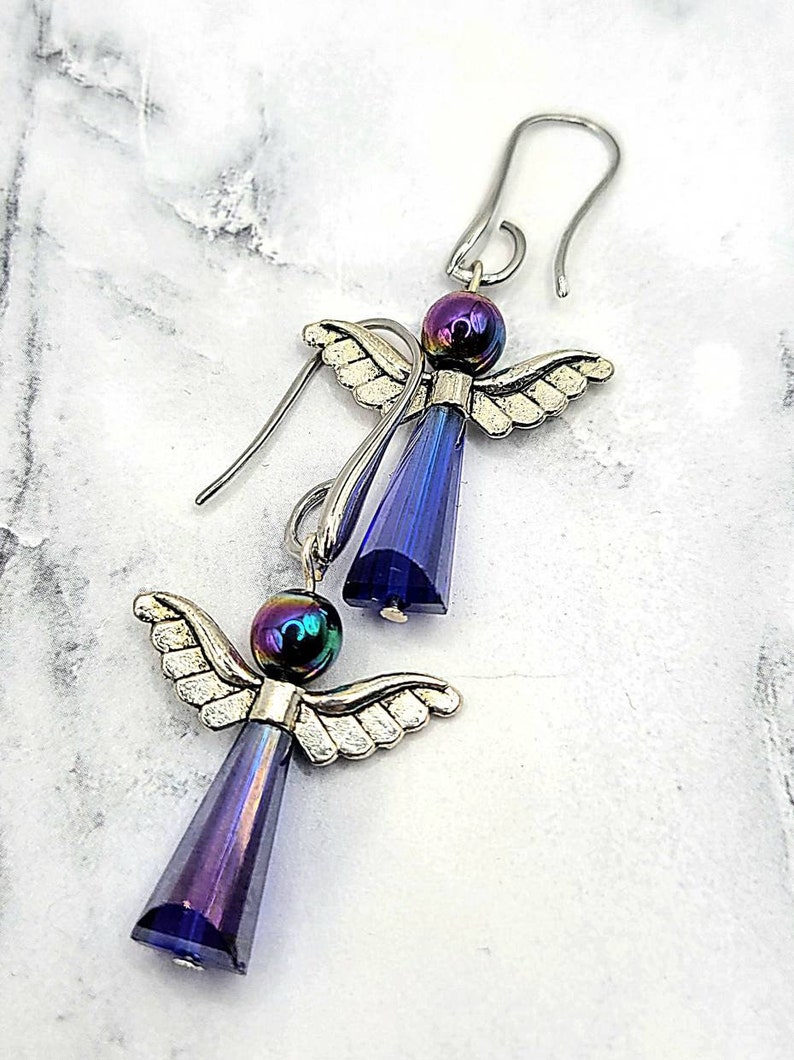 May include: A pair of silver angel earrings with iridescent blue crystal drops and black beads.
