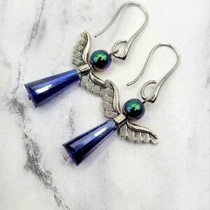 May include: A pair of silver angel wing earrings with iridescent blue beads and dark blue crystal drops.