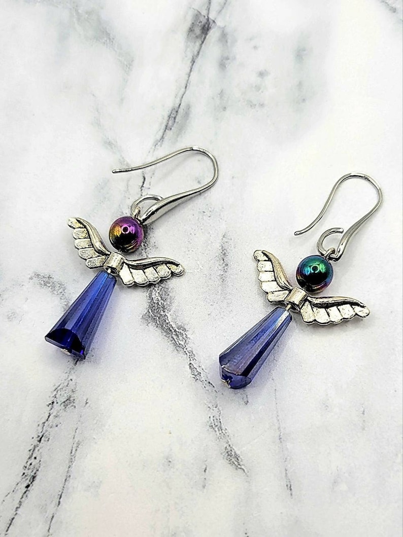 May include: A pair of silver angel wing earrings with iridescent purple beads and blue crystal drops.