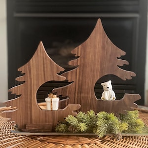 May include: Two wooden Christmas tree decorations with a white ceramic polar bear and a white ceramic gift box in the cutouts. The trees are on a silver tray with green pine sprigs.