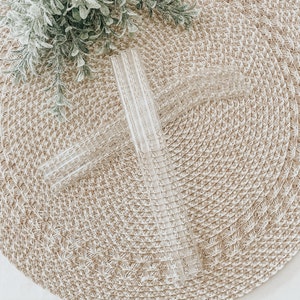 May include: Two clear glass drinking straws with a woven straw placemat background.