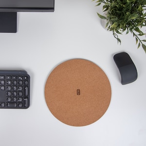 May include: A round cork mouse pad with a brown color and a small, engraved letter "E" in the center.
