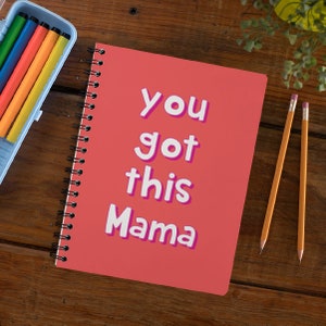 May include: A pink spiral bound notebook with the text "you got this Mama" in white with a pink outline.