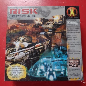 Könnte beinhalten: Eine Schachtel für das Brettspiel Risk 2210 A.D. Die Schachtel zeigt ein futuristisches Bild von Soldaten und Fahrzeugen. Der Text auf der Schachtel lautet "Risk 2210 A.D." und "Avalon Hill".