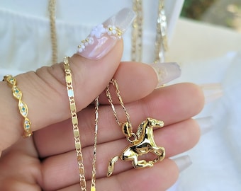 May include: A gold chain necklace with a gold horse pendant. The necklace is on a white surface.