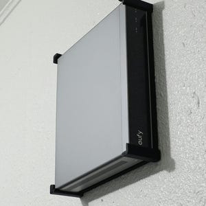 May include: A silver and black eufy security device mounted on a white wall. The device is rectangular with a silver front and black trim. The word "eufy" is printed on the side.