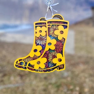 May include: Yellow rain boots with a floral pattern. The boots are made of wood and have a cutout design.