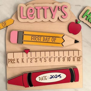 May include: Wooden school-themed sign with the text "Letty's" in pink, "Harper's" in green, and "Last Day Of" in yellow. Includes a pencil, apple, crayon, and ruler with the text "First Day Of" and "Date: 2025".