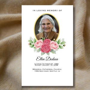 Peut inclure: Une carte commémorative blanche avec une photo d'une femme dans un cadre ovale doré. La carte est ornée de roses roses et de feuilles vertes autour de la photo. Le texte indique "En souvenir affectueux d'Ellen Dodson, Lever du soleil le 07 octobre 1965, Couché de soleil le 15 janvier 2038, Église cathédrale commémorative, 1550 Main Road, Seattle, CA."