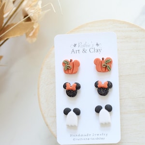 Peut inclure: Carte de bijoux faits &agrave; la main avec trois paires de boucles d'oreilles sur le th&egrave;me d'Halloween. Les boucles d'oreilles comprennent des citrouilles oranges avec des feuilles vertes, des t&ecirc;tes de Minnie Mouse noires et scintillantes avec des n&oelig;uds orange et des fant&ocirc;mes blancs.